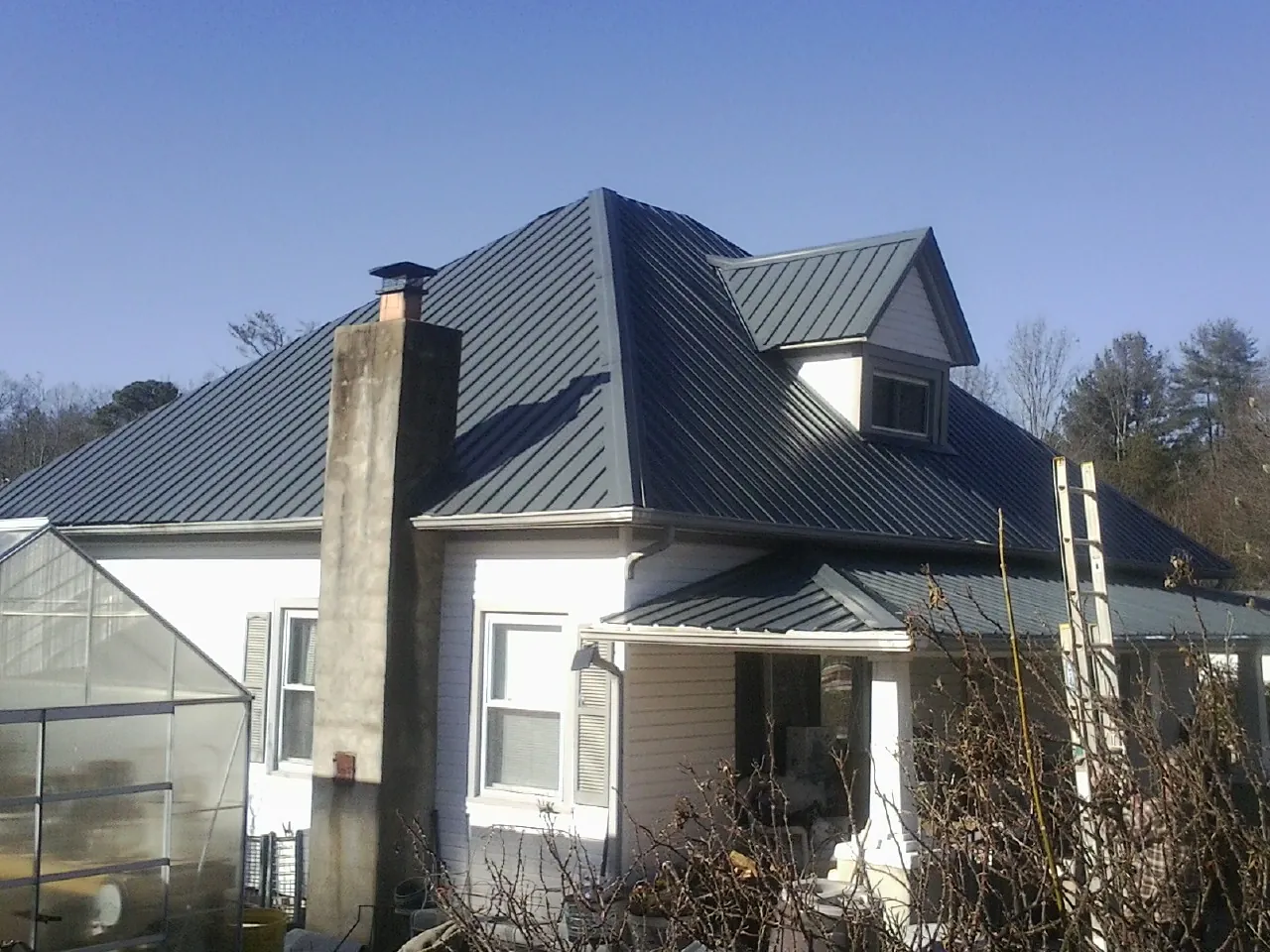 Dark blue standing seam metal roof on a white farmhouse with dormer — Slate & Tile Roof Repair by Roofing Brothers in Buffalo Valley