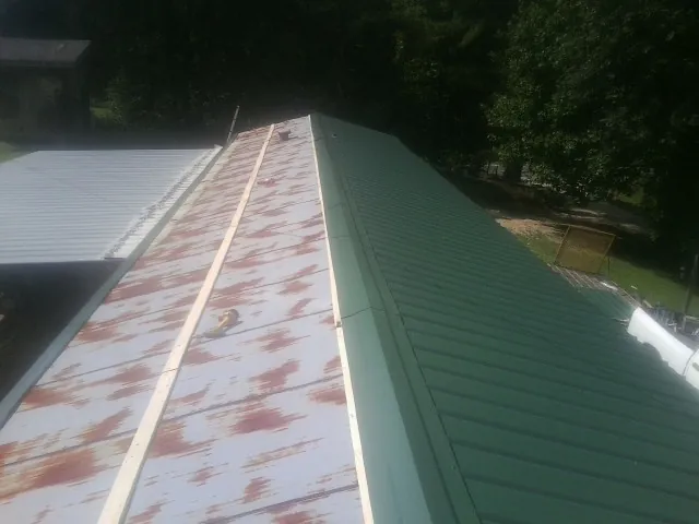Old rusted panels beside newly installed green metal roofing — Wind Damage Roof Repair by Roofing Brothers in Buffalo Valley