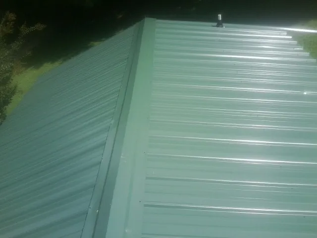 New green metal panels meeting at the ridge of a roof — Flat Roof Repair work by our crew in Buffalo Valley
