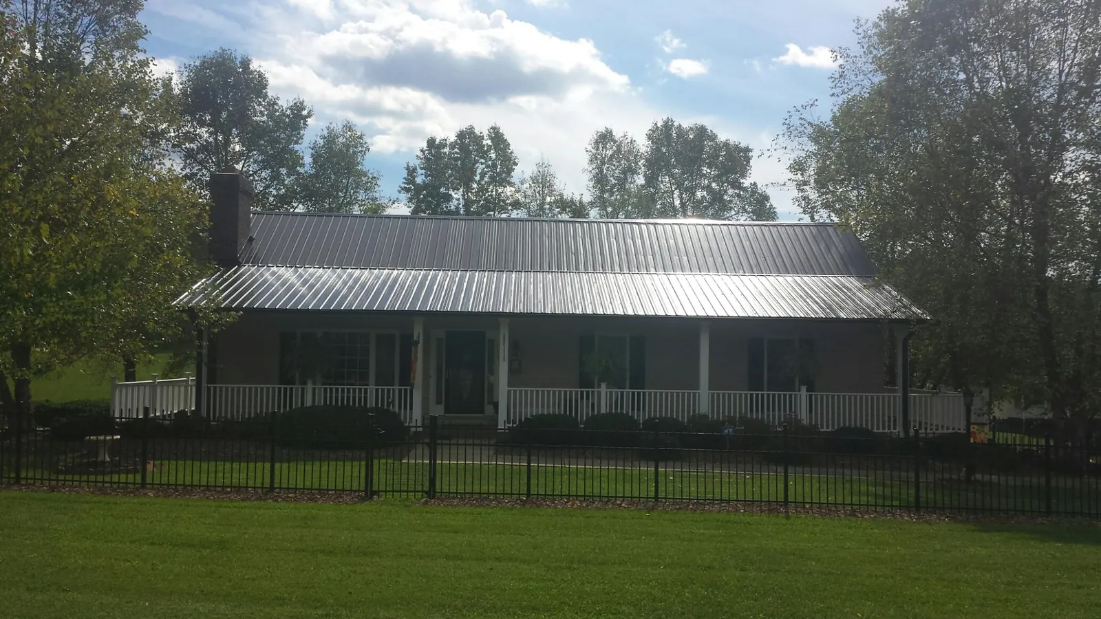 Gray metal roof on a brick ranch with a full width front porch — Gutter Guard Installation work by our crew in Buffalo Valley