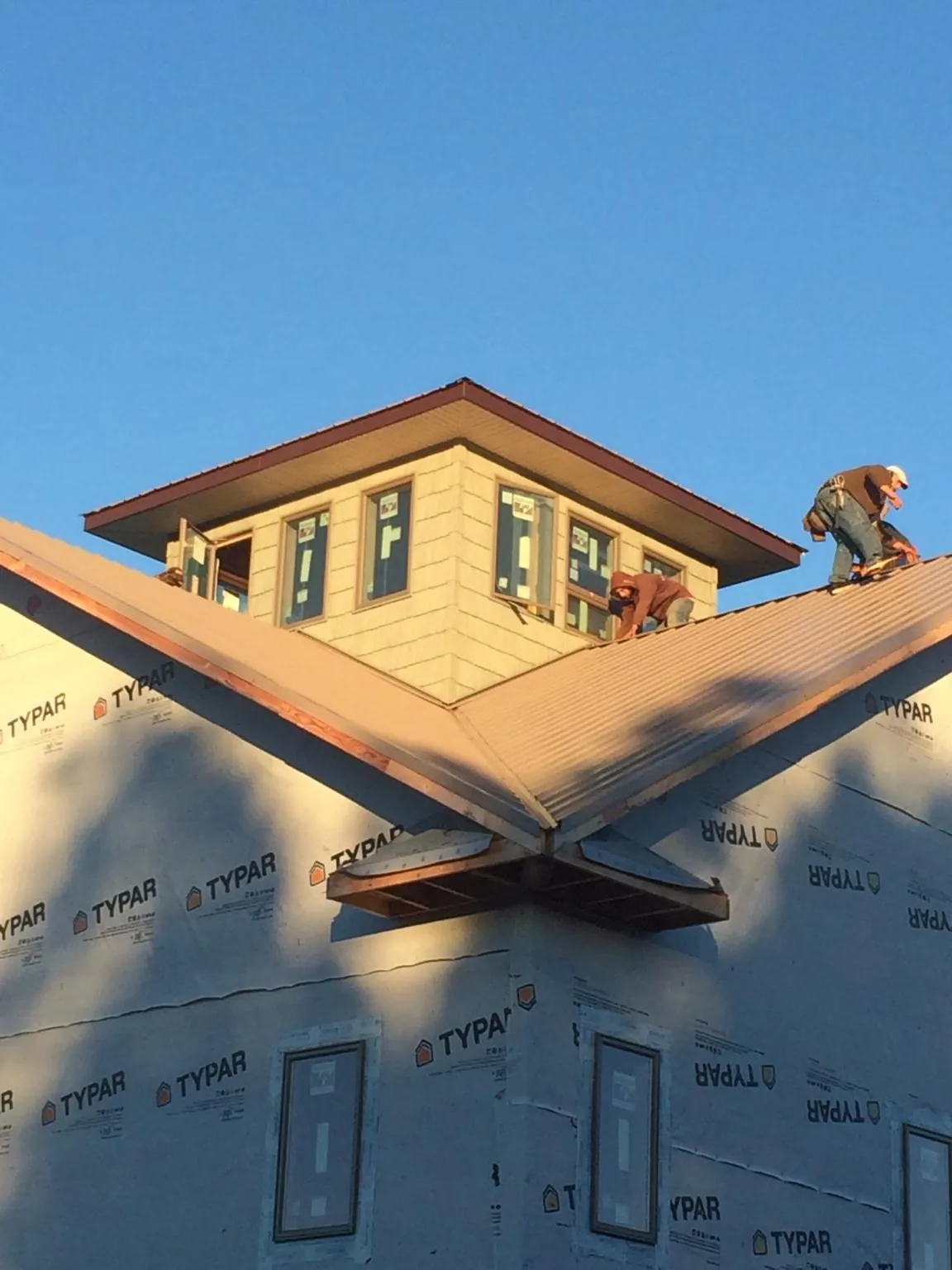 Roofers working around a rooftop cupola on a new metal roof at sunset — Roof Waterproofing in Buffalo Valley by Roofing Brothers